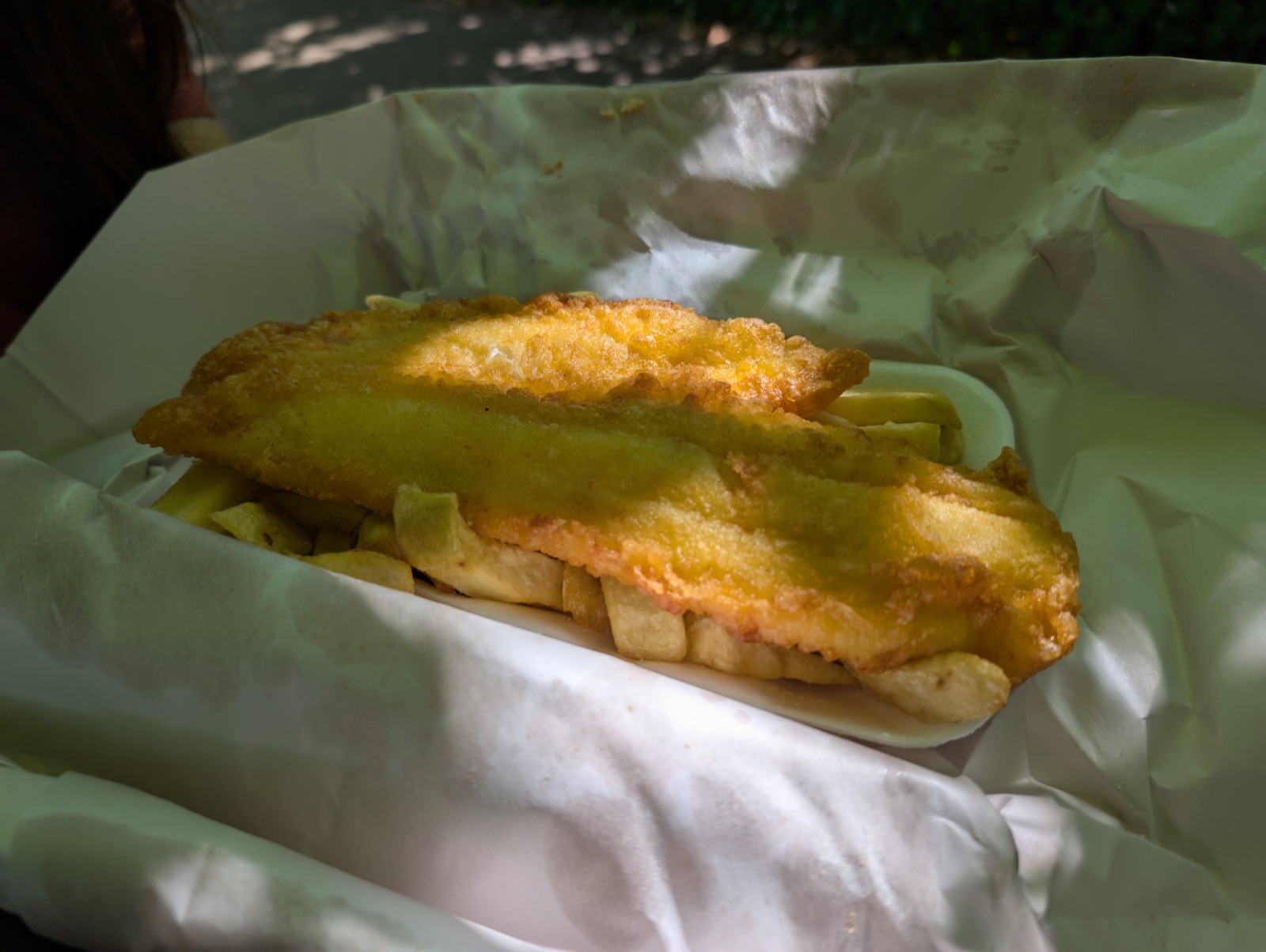 Illustrative photograph of battered cod and chips in a takeaway tray and wrapping paper